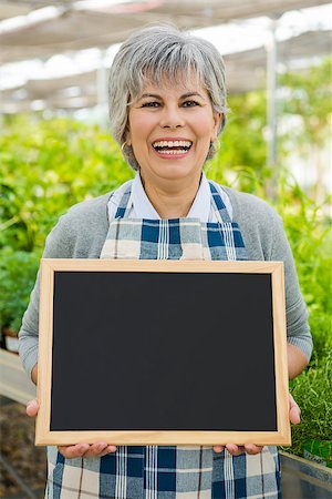 flower sale - Mature woman in a greenhouse holding a chalkboard Stock Photo - Budget Royalty-Free & Subscription, Code: 400-08289243
