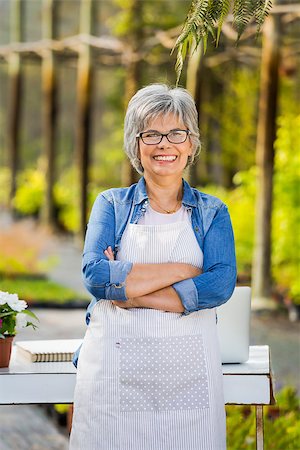 flower sale - Beautiful mature woman working in a greenhouse, looking at camera and smiling Stock Photo - Budget Royalty-Free & Subscription, Code: 400-08289269