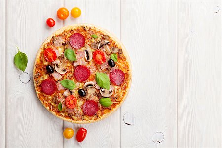 simsearch:400-08291219,k - Italian pizza with pepperoni, tomatoes, olives and basil on wooden table. Top view with copy space Stock Photo - Budget Royalty-Free & Subscription, Code: 400-08289445