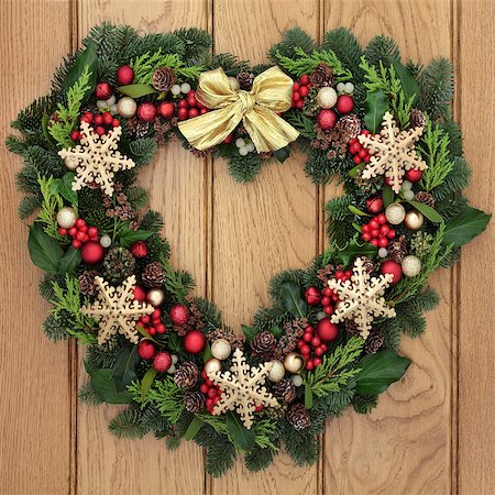 red ribbon and plant - Christmas heart shaped wreath with gold snowflake bauble decorations, bow, holly, mistletoe and winter greenery over oak front door background. Stock Photo - Budget Royalty-Free & Subscription, Code: 400-08282488