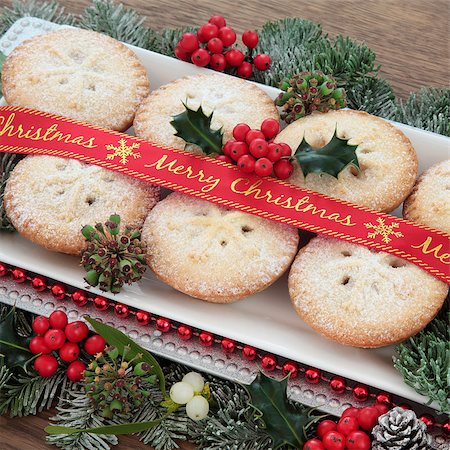 Mince pie cakes with merry christmas ribbon, holly, mistletoe and winter greenery over white background. Stock Photo - Budget Royalty-Free & Subscription, Code: 400-08282492