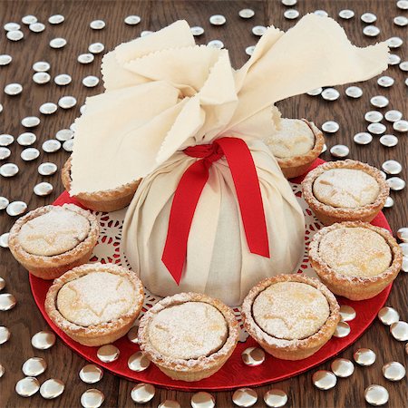 Christmas pudding in a muslin bag with mince pies and small gold sweets over oak background. Stock Photo - Budget Royalty-Free & Subscription, Code: 400-08282523