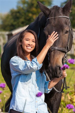 simsearch:400-08299085,k - Beautiful happy Asian Eurasian young woman or girl wearing denim shirt, smiling and leading her horse in sunshine Stock Photo - Budget Royalty-Free & Subscription, Code: 400-08294695