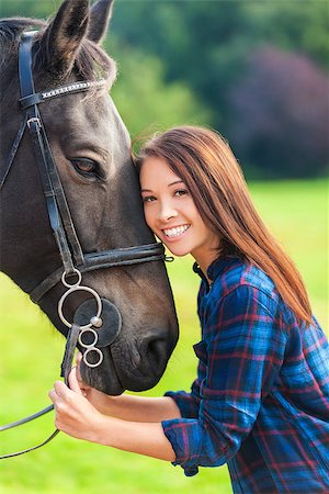 simsearch:400-08299085,k - Beautiful happy Asian Eurasian young woman or girl wearing plaid checked shirt, smiling and resting her head on her horse in sunshine Stock Photo - Budget Royalty-Free & Subscription, Code: 400-08295331