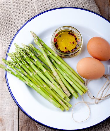 Fresh asparagus, olive oil and eggs on a white enamel plate. Photographie de stock - Aubaine LD & Abonnement, Code: 400-08297704
