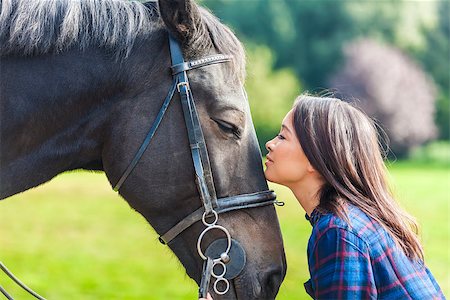 simsearch:400-08299085,k - Beautiful happy Asian Eurasian young woman or girl wearing plaid checked shirt, smiling and resting her head on her horse in sunshine Stock Photo - Budget Royalty-Free & Subscription, Code: 400-08298184