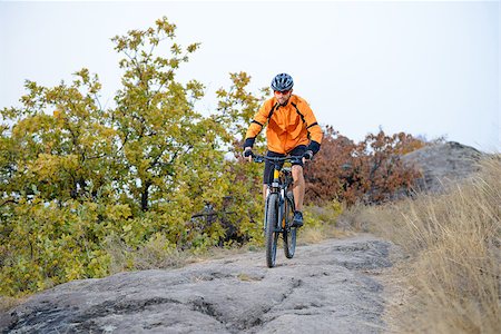 Cyclist in Orange Wear Riding Bike on the Beautiful Autumn Mountain Trail Stock Photo - Budget Royalty-Free & Subscription, Code: 400-08298521