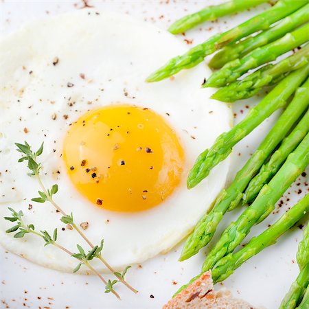 Green asparagus with fried egg and bread with butter on a white plate. Photographie de stock - Aubaine LD & Abonnement, Code: 400-08298650