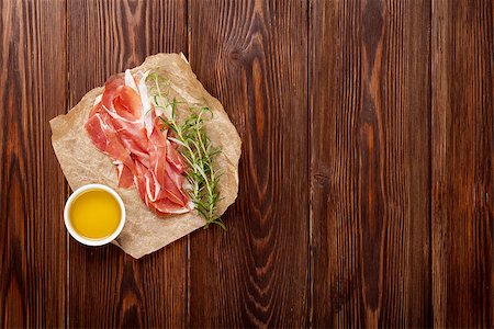 smoked ham - Prosciutto with rosemary and olive oil on wooden table. Top view with copy space Foto de stock - Super Valor sin royalties y Suscripción, Código: 400-08298824