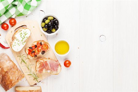 simsearch:400-08291219,k - Bruschetta with cheese, tomatoes and prosciutto on cutting board. Top view with copy space Stock Photo - Budget Royalty-Free & Subscription, Code: 400-08291221