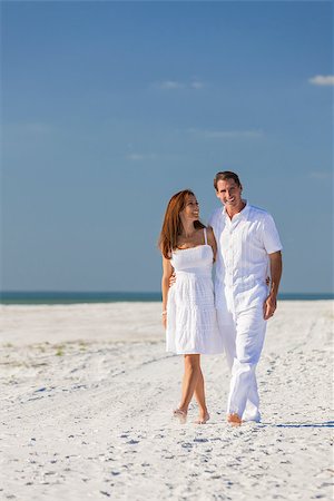 Romantic man and woman romantic couple in white clothes walking on a deserted tropical beach with bright clear blue sky Stock Photo - Budget Royalty-Free & Subscription, Code: 400-08291848