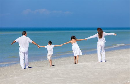 simsearch:400-04235471,k - Rear view of happy family of mother, father and two children, son and daughter, walking holding hands and having fun in the sand on a sunny beach Stock Photo - Budget Royalty-Free & Subscription, Code: 400-08292390