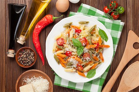 pasta dish with olives on white background - Colorful penne pasta with tomatoes and basil on wooden table. Top view Stock Photo - Budget Royalty-Free & Subscription, Code: 400-08293314