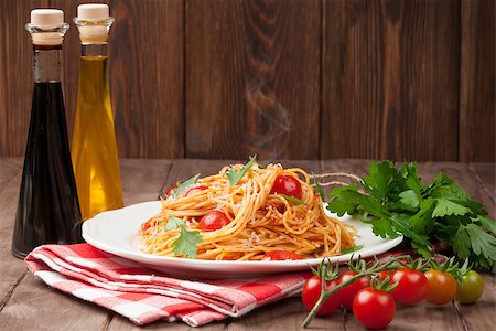 pasta dish with olives on white background - Spaghetti pasta with tomatoes and parsley on wooden table Stock Photo - Budget Royalty-Free & Subscription, Code: 400-08293317