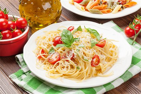 pasta dish with olives on white background - Spaghetti and penne pasta with tomatoes and basil on wooden table Stock Photo - Budget Royalty-Free & Subscription, Code: 400-08300730