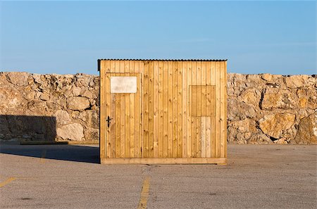 photojope (artist) - Closed wooden cabin. Transportable new shelter on varnished yellow wood located on an asphalt parking in a sunny day. Photographie de stock - Aubaine LD & Abonnement, Code: 400-08317155