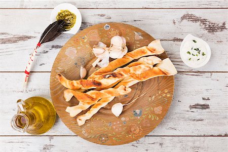 pane all'aglio - Pizza breadsticks on white wooden background with olive oil and garlic basil dip. Culinary pizza eating. Fotografie stock - Microstock e Abbonamento, Codice: 400-08317955