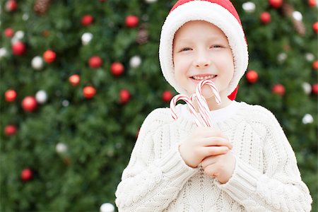 silly winter boy - positive little boy in santa's hat holding candy canes ready for festive christmas time Stock Photo - Budget Royalty-Free & Subscription, Code: 400-08318039