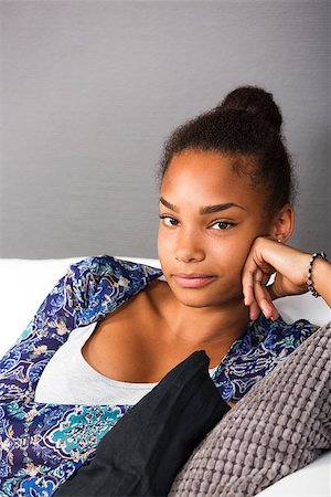 Teenage girl sitting in a couch looking into camera with a friendly smile Stock Photo - Budget Royalty-Free & Subscription, Code: 400-08318655