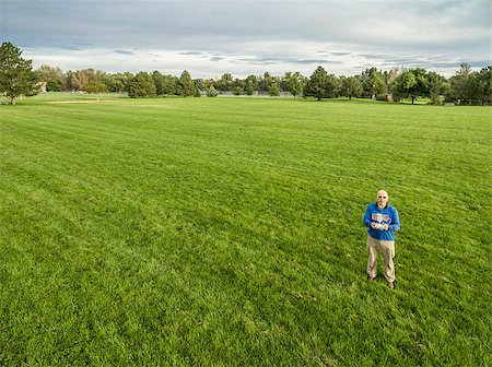 aerial shot of a male drone operator with a remote radio controller on a green grassy field Stock Photo - Budget Royalty-Free & Subscription, Code: 400-08334099