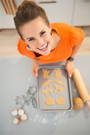 rolling over - Funny modern housewife holding tray of uncooked Halloween biscuits in kitchen. Halloween treats ready to go into oven. Traditional autumn holiday. Upper view Stock Photo - Budget Royalty-Free & Subscription, Code: 400-08336568