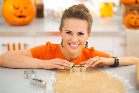 simsearch:400-08336563,k - Happy young housewife cutting out Halloween cookies with pastry cutter from rolled pastry in kitchen decorated for horror party night. Traditional autumn holiday Stock Photo - Budget Royalty-Free & Subscription, Code: 400-08336576