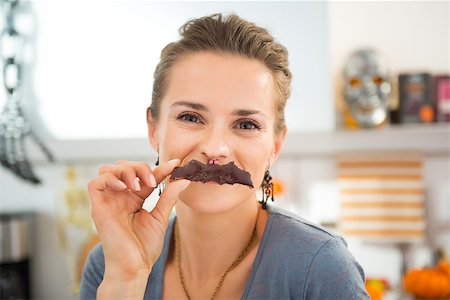 simsearch:400-08336563,k - Funny modern housewife in decorated kitchen making mustache with homemade Halloween biscuit in shape of bat Foto de stock - Royalty-Free Super Valor e Assinatura, Número: 400-08337746