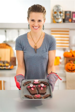 simsearch:400-08336563,k - Happy modern housewife in decorated kitchen showing off freshly baked Halloween biscuits for Trick or Treat. Ready to halloween party. Traditional autumn holiday Stock Photo - Budget Royalty-Free & Subscription, Code: 400-08337747