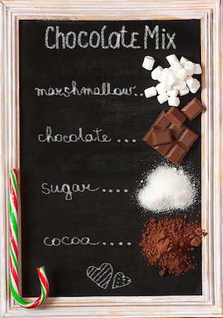 simsearch:400-08338402,k - Hot chocolate mix on old chalk blackboard. Sweet marshmallow, chocolate bars, sugar, cocoa powder and mint candy cane for cooking winter holiday drink. Foto de stock - Super Valor sin royalties y Suscripción, Código: 400-08338397