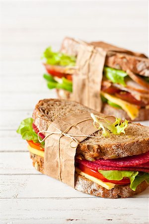 sandwich rustic table - Two delicious sandwiches wrapped in papper and tied with kitchen twine. Selective focus. Foto de stock - Super Valor sin royalties y Suscripción, Código: 400-08338454
