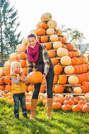 simsearch:400-07916492,k - Beautiful woman with little girl holding pumpkins in front of pumpkin pyramid on farm during the autumn season Stock Photo - Budget Royalty-Free & Subscription, Code: 400-08339778