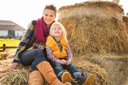 simsearch:400-07916492,k - Portrait of happy woman with cute child sitting on the hay on farm on sunny autumn day Stock Photo - Budget Royalty-Free & Subscription, Code: 400-08339779