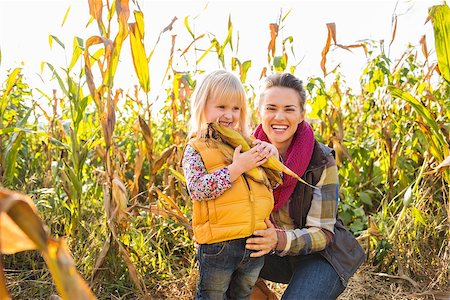 Portrait of young woman and child biting kennel in corn field on farm during the autumn season Stock Photo - Budget Royalty-Free & Subscription, Code: 400-08339787