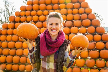 simsearch:400-07916492,k - Portrait of smiling young woman holding pumpkins in front of big pyramid of pumpkins in autumn outdoors Stock Photo - Budget Royalty-Free & Subscription, Code: 400-08339788