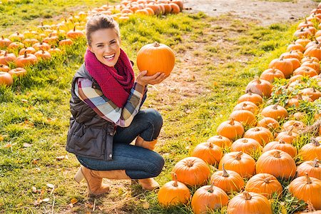 simsearch:400-07916492,k - Portrait of beautiful smiling woman next to rows of pumpkins and choosing pumpkin on pumpkin patch on farm during the autumn season Stock Photo - Budget Royalty-Free & Subscription, Code: 400-08339782