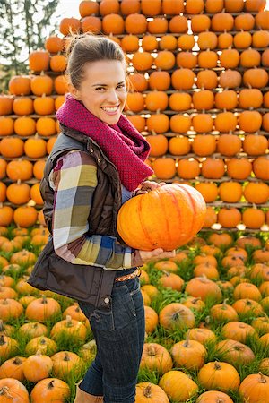 simsearch:400-07916492,k - Portrait of beautiful smiling woman holding pumpkin in front of pumpkin rows on farm during the autumn season Stock Photo - Budget Royalty-Free & Subscription, Code: 400-08339795