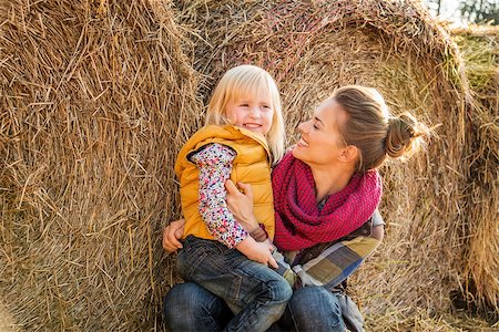simsearch:400-07916492,k - Portrait of a beautiful smiling woman and happy child sitting next to a haystack on farm during the autumn season Stock Photo - Budget Royalty-Free & Subscription, Code: 400-08339798