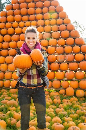 simsearch:400-07916492,k - Portrait of smiling beautiful woman holding pumpkins in front of pumpkins rows in autumn outdoors Stock Photo - Budget Royalty-Free & Subscription, Code: 400-08339790