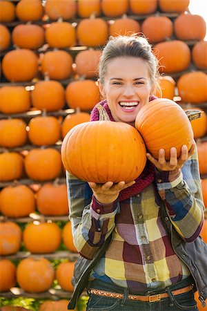 simsearch:400-07916492,k - Portrait of young smiling beautiful woman holding pumpkins in front of big pyramid of pumpkins on farm during the autumn season Stock Photo - Budget Royalty-Free & Subscription, Code: 400-08339791