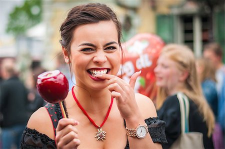 simsearch:649-03775322,k - Attractive young woman in traditional Dirndl dress holding a red caramelized apple at the Oktoberfest with people in the background. Foto de stock - Super Valor sin royalties y Suscripción, Código: 400-08332754