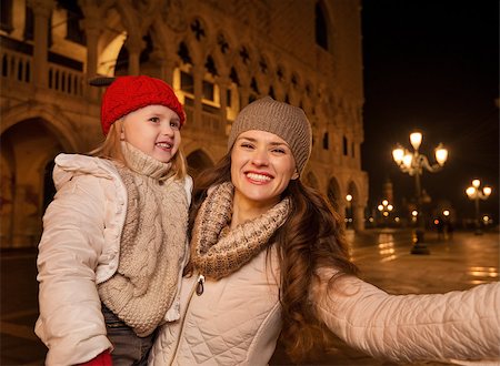 simsearch:400-08344334,k - Holiday family trip to Venice, Italy can change the whole Christmas experience. Happy mother with child taking selfie while standing on Piazza San Marco in the evening. Winter Tourism Stock Photo - Budget Royalty-Free & Subscription, Code: 400-08344331