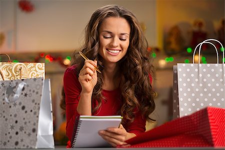 shopping bags in kitchen - Christmas holidays are a time of gift-giving. Shopping list can make Christmas season easy and save time for more fun. Happy young woman among shopping bags with pen and notebook checking list Stock Photo - Budget Royalty-Free & Subscription, Code: 400-08344489
