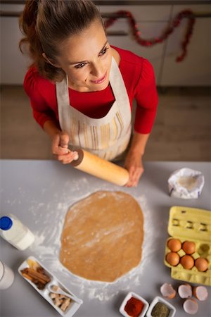 simsearch:400-08336563,k - Christmas season can inspire you in the kitchen and you may want to treat your family with edible gifts. Young housewife holding rolling pin. There are roll out dough, eggs and spices on a table. Foto de stock - Royalty-Free Super Valor e Assinatura, Número: 400-08344495