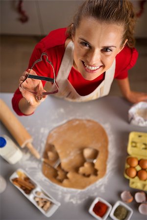 simsearch:400-08336563,k - Christmas season can inspire you in the kitchen and you may want to treat your family with edible gifts. Modern young housewife showing cookie cutter. She is making Christmas themed cookies Stock Photo - Budget Royalty-Free & Subscription, Code: 400-08344496