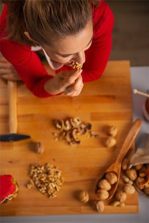 simsearch:400-08336563,k - Christmas season can inspire you in the kitchen and you may want to treat your family with edible gifts. Upper view on housewife taking a bite of walnut while making nuts in honey sweets Foto de stock - Royalty-Free Super Valor e Assinatura, Número: 400-08344499