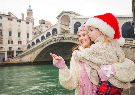 simsearch:400-07954337,k - Small family trip is another way how to make Christmas holidays even more appealing. Happy mother pointing on something to child wearing Santa Hat while standing in the front of Ponte di Rialto Stock Photo - Budget Royalty-Free & Subscription, Code: 400-08345245