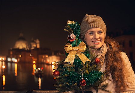 simsearch:400-08344334,k - Tune in for charming Christmas time in Venice, Italy. Happy young woman with a Christmas tree standing on a bridge overlooking Grand canal and looking into distance Stock Photo - Budget Royalty-Free & Subscription, Code: 400-08345285