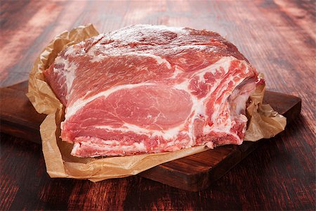 Pork neck piece on baking paper on brown wooden chopping board on brown wooden background. Culinary meat eating. Stock Photo - Budget Royalty-Free & Subscription, Code: 400-08345784