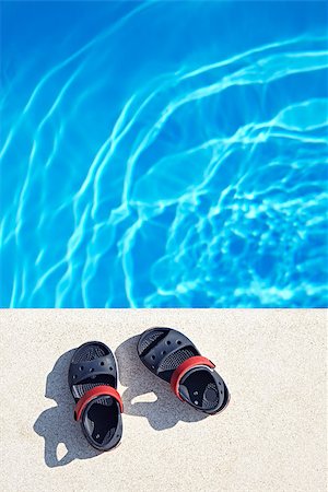 Pair of baby sandals at the swimming pool at sunny day. Copy space. Stock Photo - Budget Royalty-Free & Subscription, Code: 400-08340084