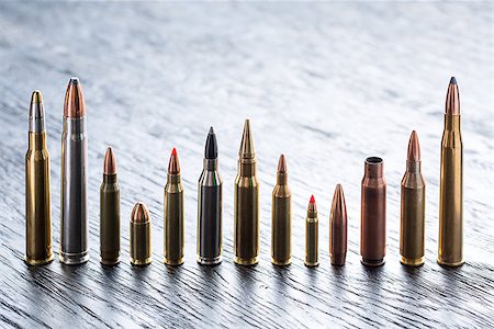 simsearch:400-04577380,k - Number of large-caliber ammunition of different caliber in one line on a dark textural wooden background. Studio shot. Fotografie stock - Microstock e Abbonamento, Codice: 400-08340612